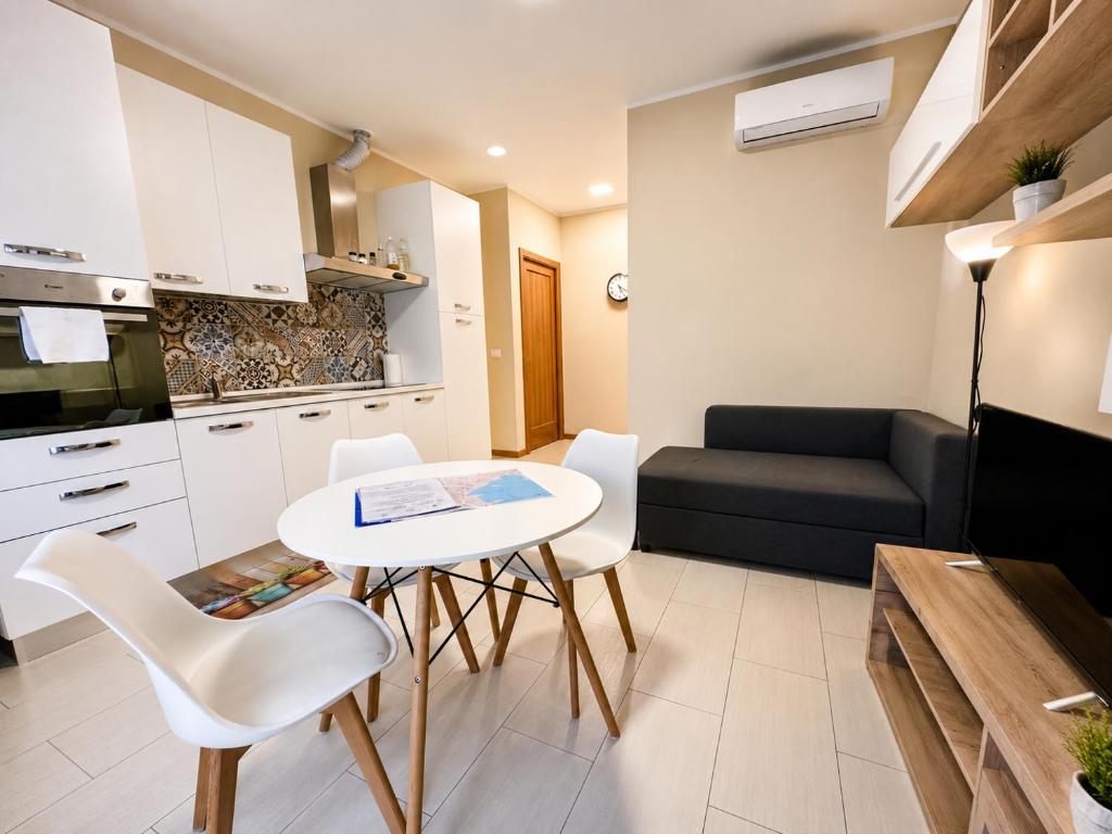 Grab a Flat in Coroneo في ترييستي: مطبخ وغرفة معيشة بها طاولة وكراسي