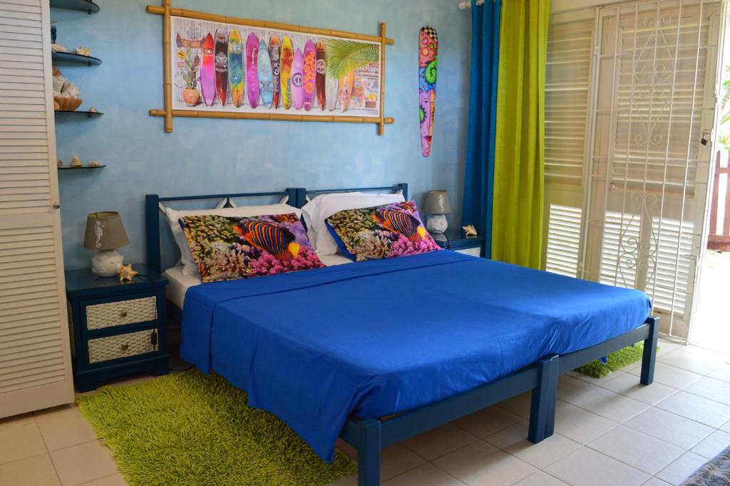 a bedroom with a blue bed with colorful pillows at Green Garden Apartment in Christ Church
