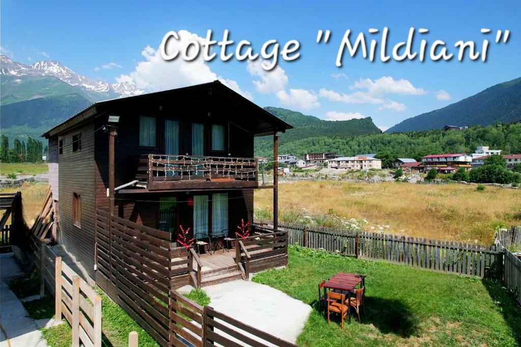 a small house with a porch and a fence at Cottage Mildiani in Mestia