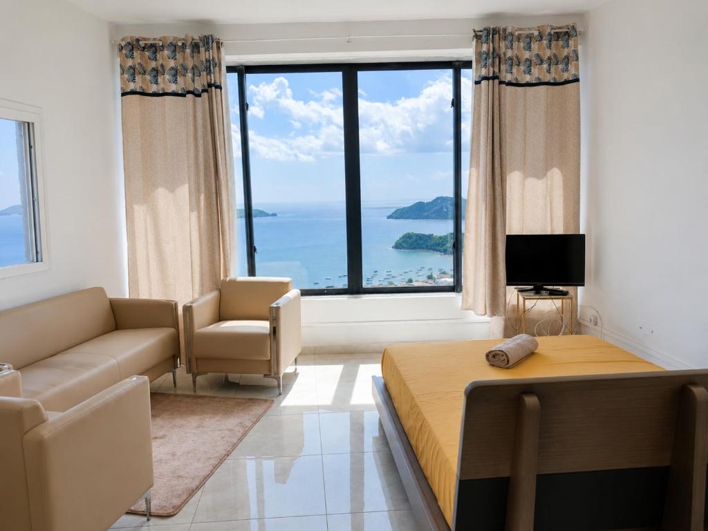 a bedroom with a bed and a couch and a large window at Studio cosy vue sur mer in Mtsamboro
