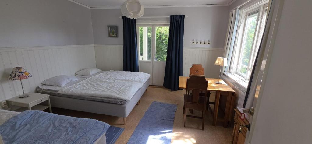a bedroom with two beds and a desk and windows at Vandrarhemmet Tallbacka/Ängelsberg Hostel in Ängelsberg