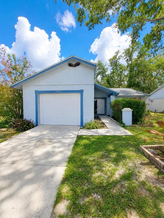 a white house with a garage on a driveway at Cozy Tampa Home in Tampa