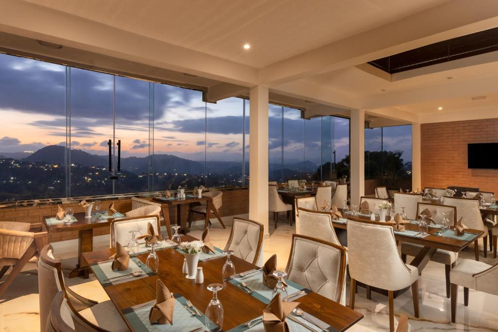 a restaurant with tables and chairs and large windows at Sunset Heaven Boutique in Kandy
