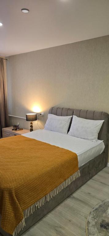 a bedroom with a large bed with an orange blanket at Yellow Apartment Mažeikiai in Mažeikiai