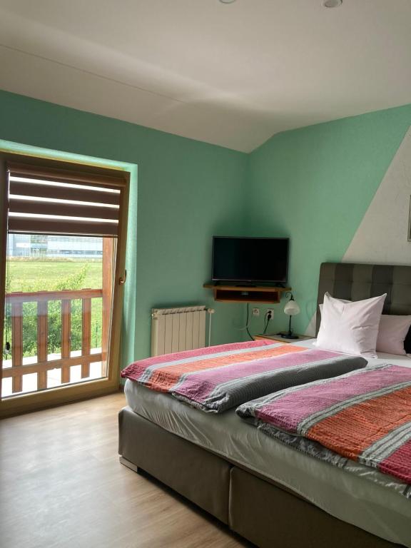 a bedroom with a bed with a television and a window at Penzion Kohout in Nýrsko