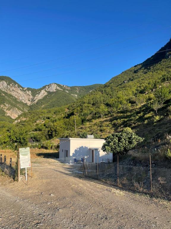a building on a dirt road with mountains in the background at Bujtina Dalmacia 2 in Shkodër