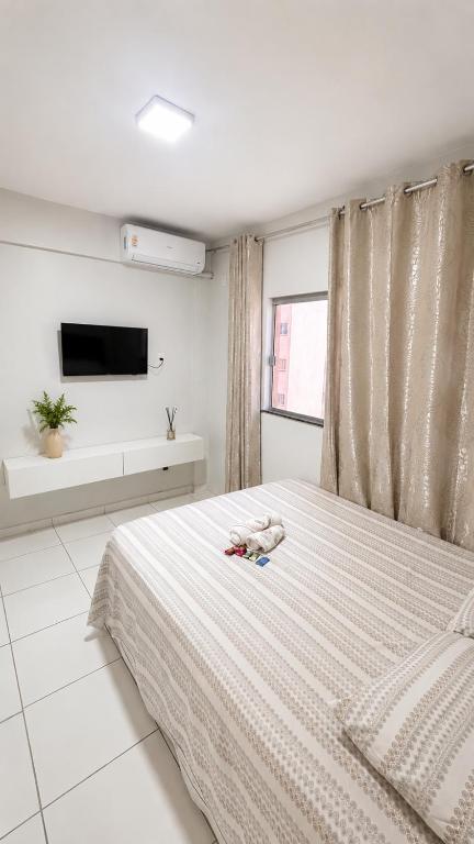 a white bedroom with a bed and a tv at Studio Moderno e Aconchegante , Centro Unai in Unaí