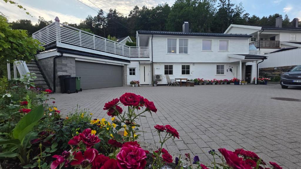 a white house with red flowers in front of it at Gjestehus i Tveit in Kristiansand