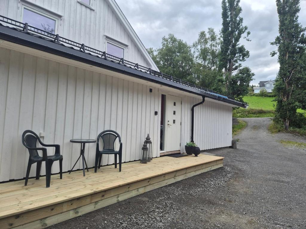a porch with two chairs and a table on the side of a house at Utleiebolig Fannrem in Fannrem