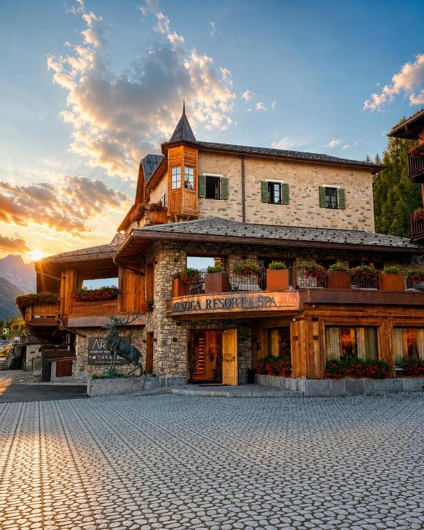 a building on a street with a sunset in the background at Arnoga Mountain View Resort & SPA in Valdidentro