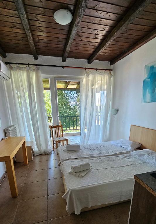 a bedroom with two beds and a table and a window at Sithonia Mare Hotel in Gerakini