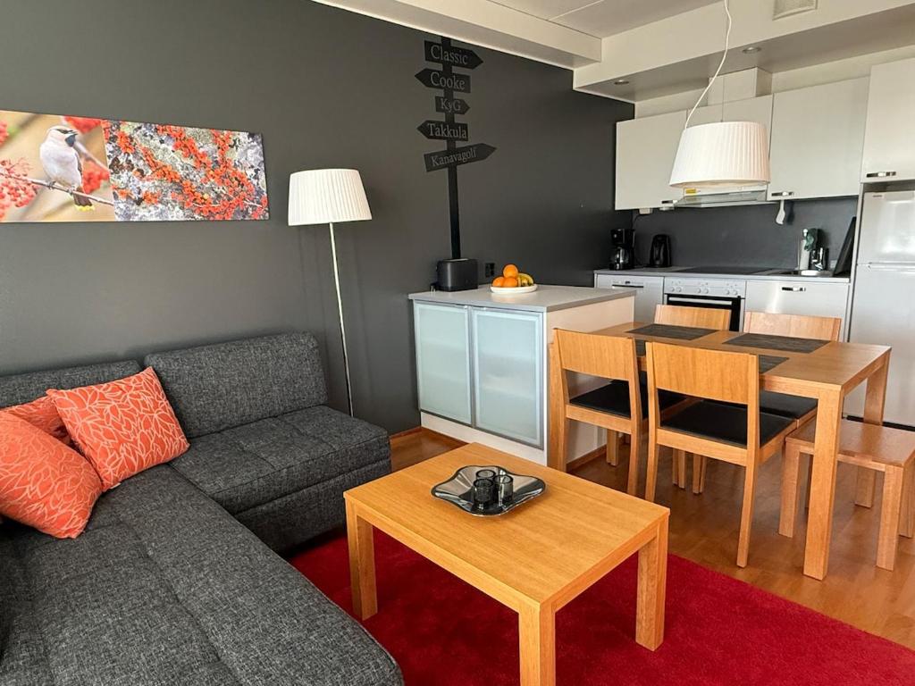 a living room with a couch and a table and a kitchen at Chalet in Vierumäki with golf course view in Lahti