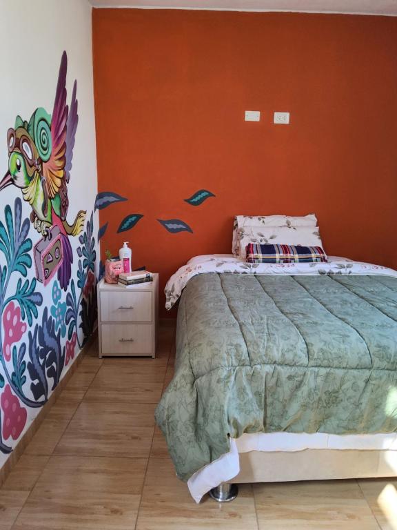a bedroom with a bed with an orange wall at Casa hogareña Pequeña in Ica