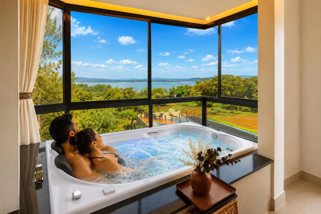 a couple in a bath tub with a large window at Pousada com piscina, jacuzzi e com vista em Capitólio - Casa Decore in Capitólio
