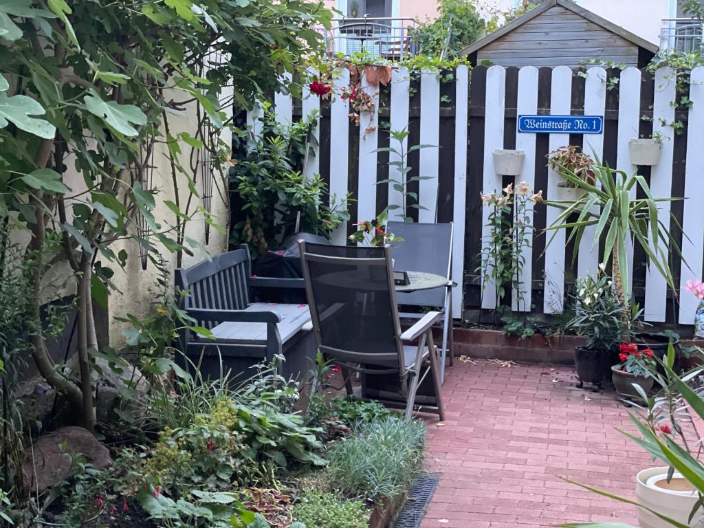 a garden with two chairs and a table and a fence at Ferienwohnung Weinstrasse in Rostock