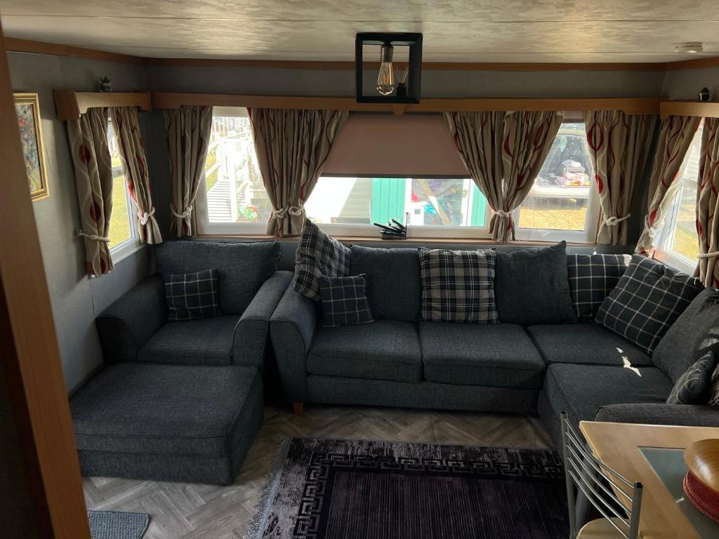 a living room with a couch and windows at Kings caravan park A-27 in Skegness