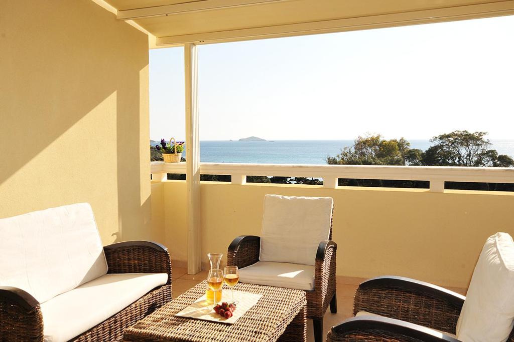 a balcony with chairs and a table with wine glasses at Aithra -Agios Petros Andros in Gavrio