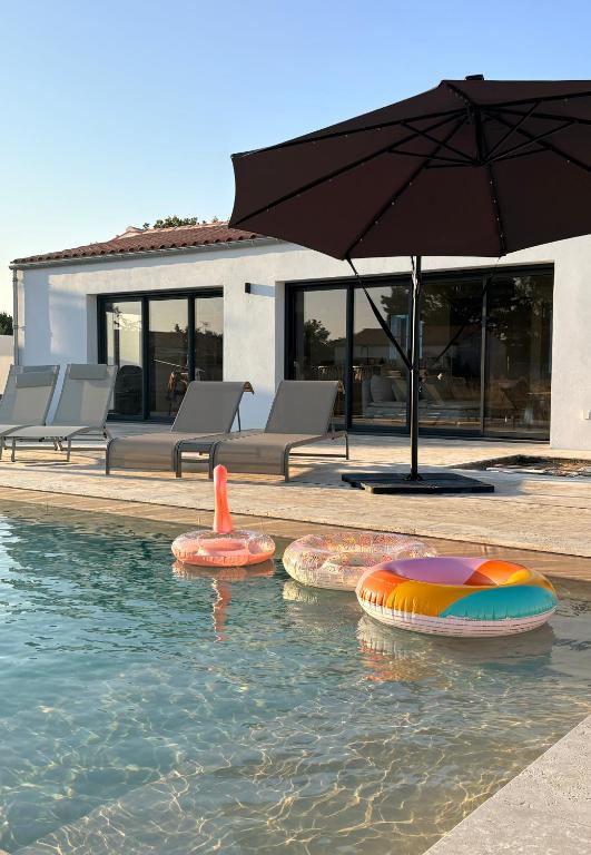a swimming pool with three inflatable objects in the water at Doudou House in Saint-Denis-dʼOléron