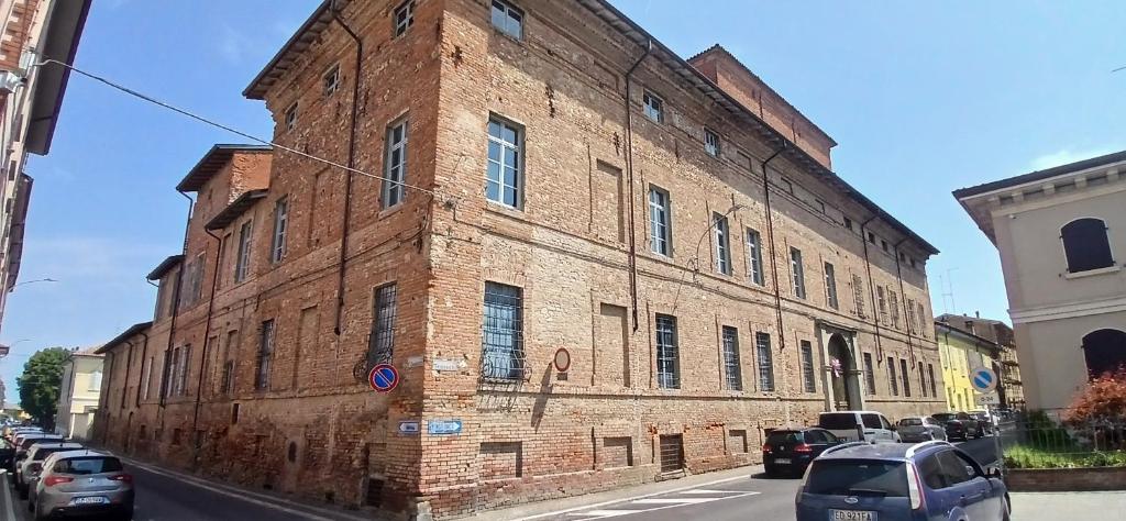 an old brick building with cars parked on a street at Palazzo TEDESCHI in Borgonovo Val Tidone
