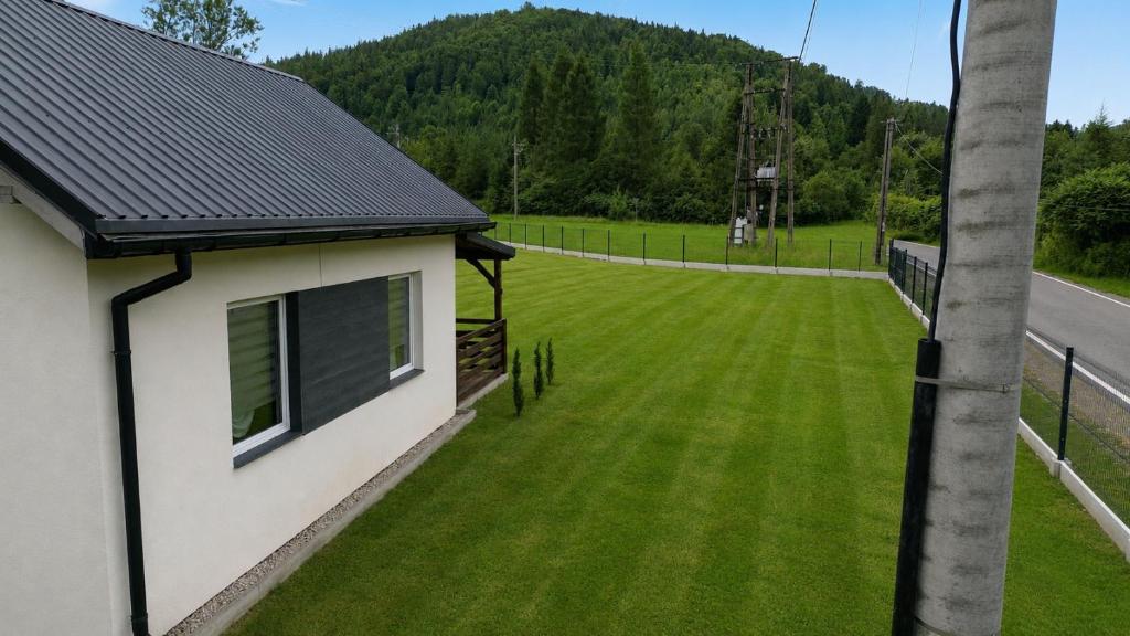 a yard with green grass next to a house at Domek na Roztokach in Rycerka Górna