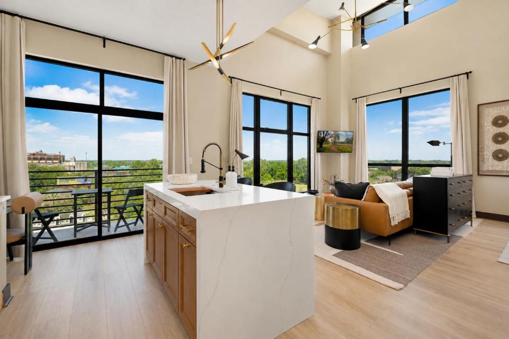 a kitchen with a counter and a living room with windows at The Eighth Luxury Penthouse in Fourth Ward in Charlotte