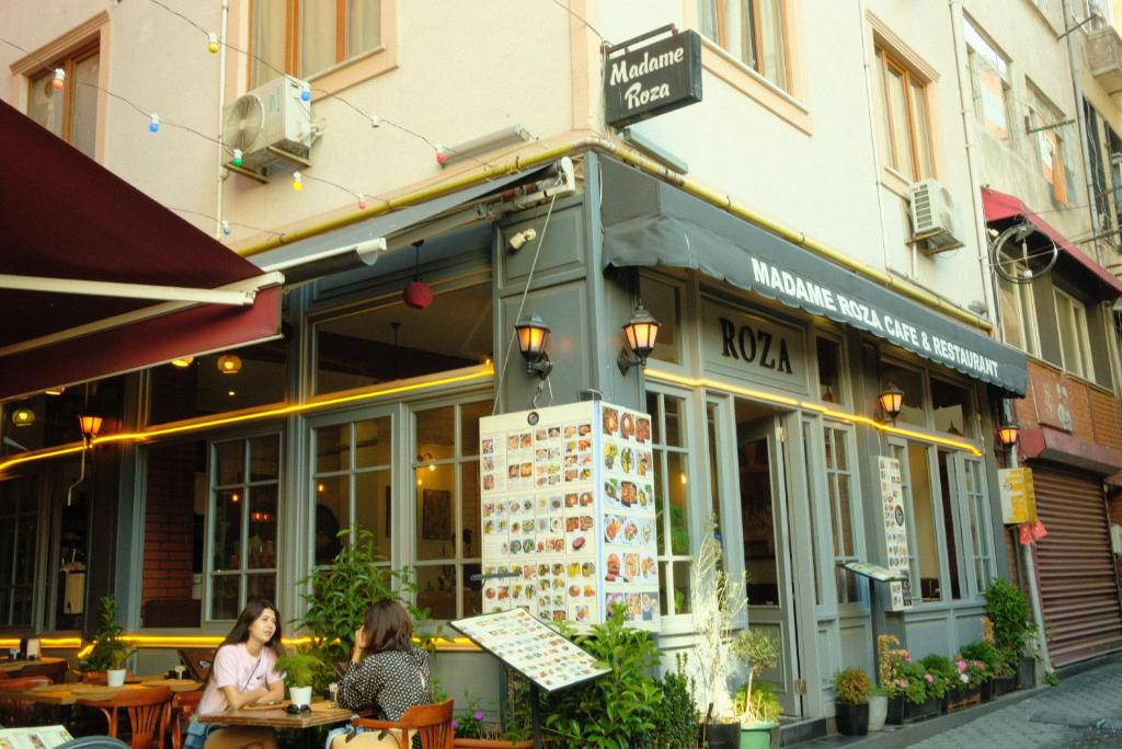 two women sitting at tables outside of a restaurant at madame roza in Istanbul