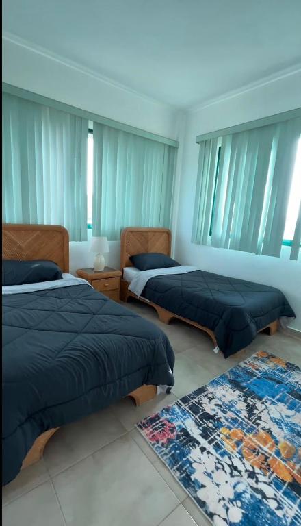 two beds in a room with windows and a rug at Residencia manatial in La Mira