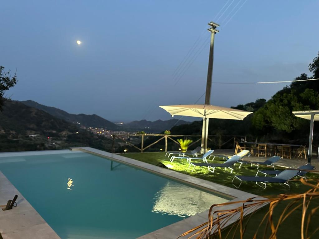 a swimming pool with two chairs and an umbrella at Villa Luca e Vale in Graniti