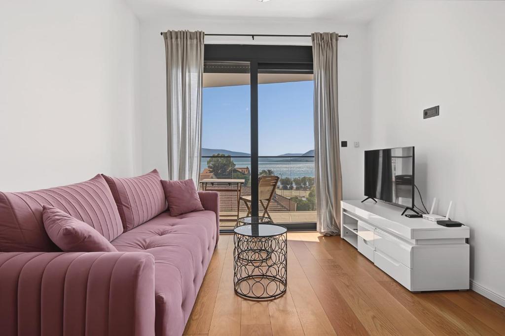 a living room with a purple couch and a television at Azure Bay Apartments in Donja Lastva