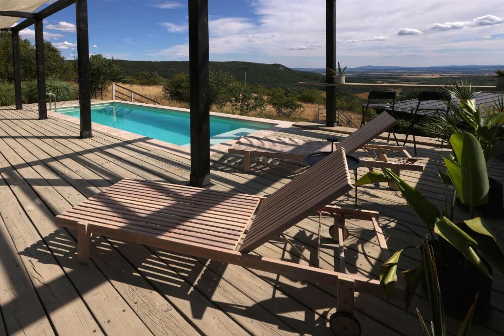 a wooden deck with a bench and a swimming pool at Ateliéry Nad Závozom in Hrušov