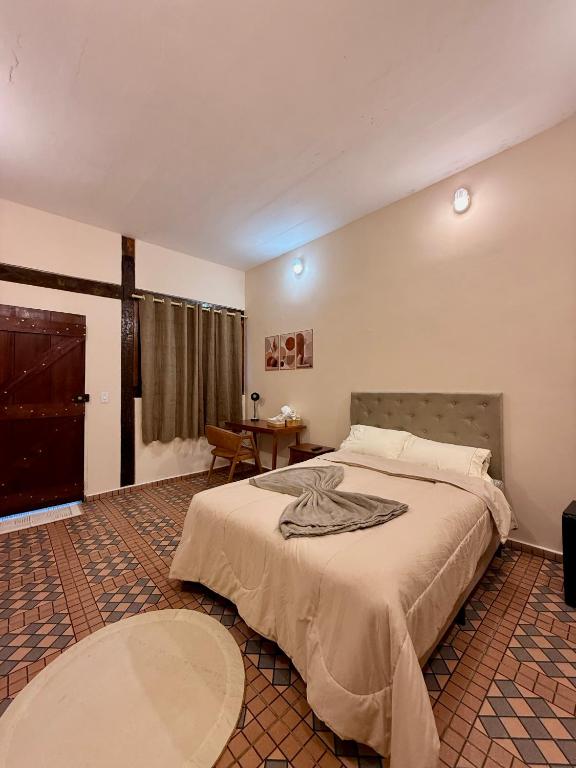 a bedroom with a large bed and a table at Pousada Nhá Luz in Salesópolis