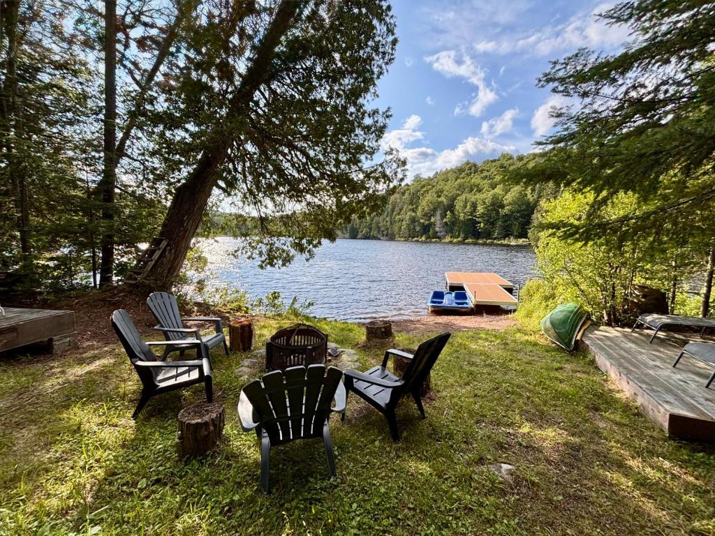a group of chairs sitting on the grass near a lake at L'Opie in Saint Adolphe D'Howard
