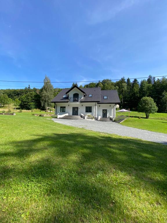 a house in a field with a gravel driveway at Apartamenty ARNIKA z sauną zewnętrzną in Lądek-Zdrój
