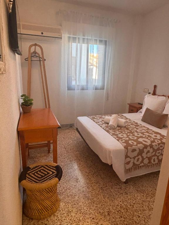 a bedroom with a bed and a table and a window at Hostal Avenida Pozo Alcón in Pozo Alcón