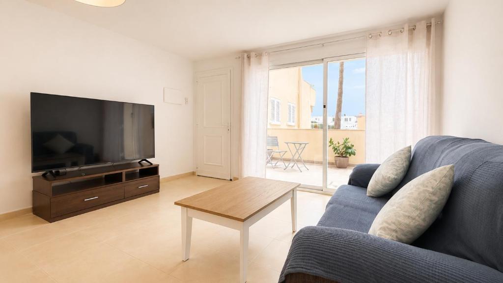 a living room with a blue couch and a flat screen tv at Apartment with pool in Cala Millor in Cala Millor