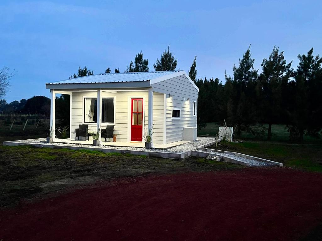a small white tiny house with a red door at Carmela, Colonia Estrella in Carmelo