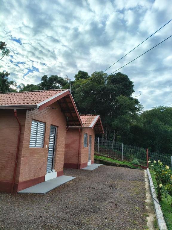 a small brick house with a car driveway at Recanto Raios do Sol in Caldas
