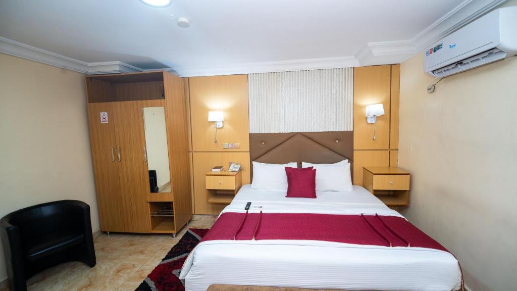 a hotel room with a large bed with red pillows at Charriot Hotels in Abuja