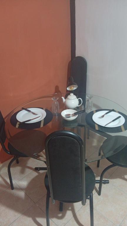 a dining room table with chairs and a glass table with plates andoverty at Studio Royal Trianon Centro in Campos dos Goytacazes