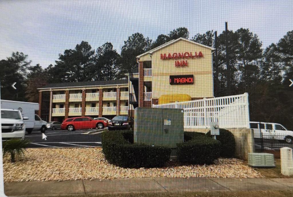 a hotel with a sign in a parking lot at Magnolia Inn in Stockbridge