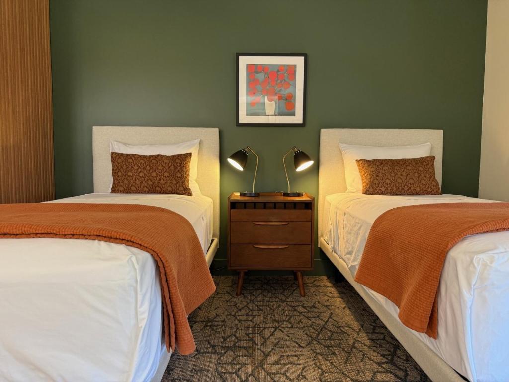 two beds in a room with green walls at Artisan Suites on Bowen in Bowen Island