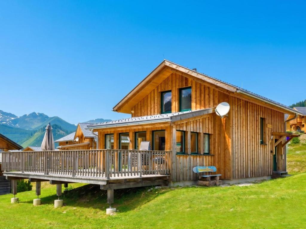 a wooden house with a deck and mountains in the background at Heidi und Peter in Hohentauern