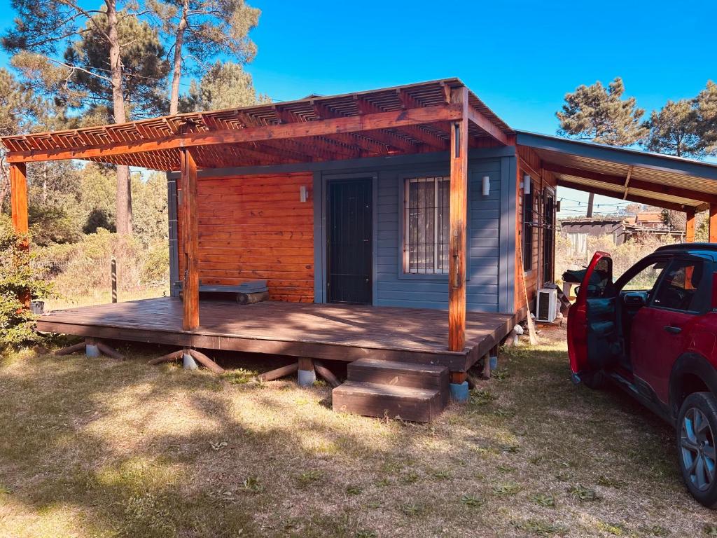 a small cabin with a wooden porch with a car parked outside at Tejanos in La Paloma