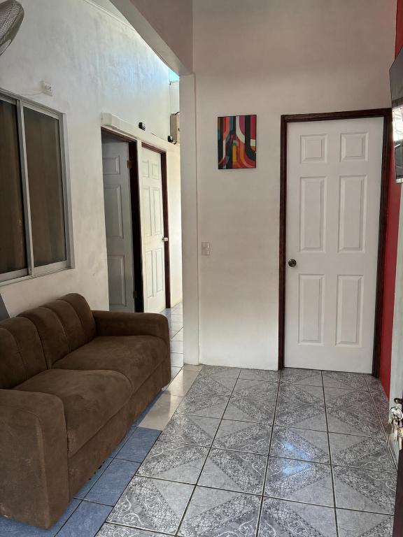 a living room with a couch and a white door at Buganvilla No 3 Aire Acondicionado in Quepos