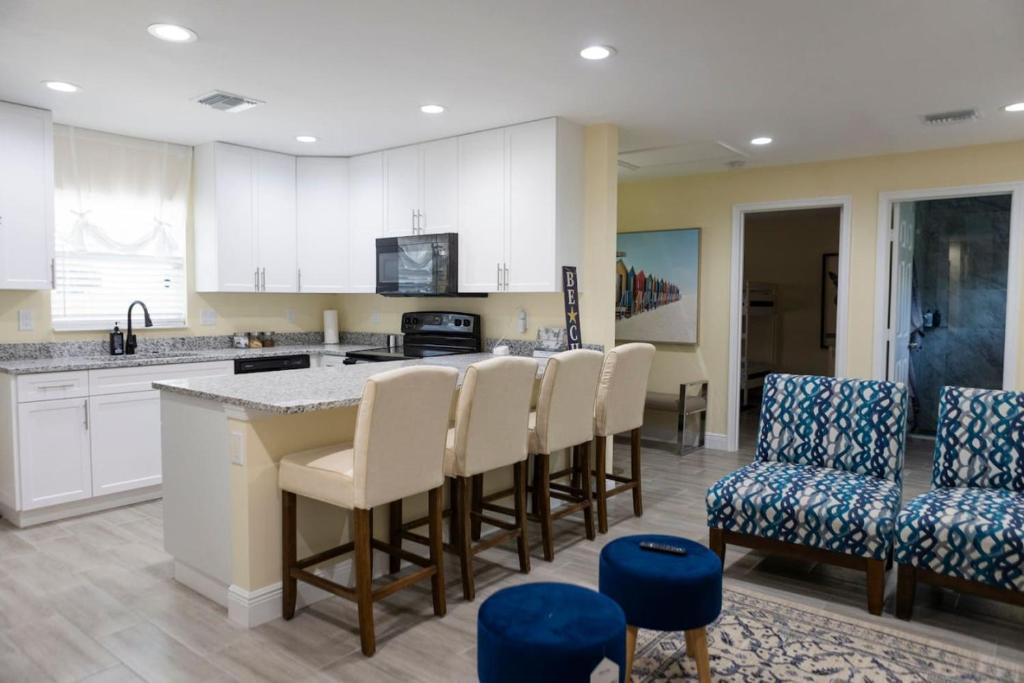 a kitchen with white cabinets and a bar with chairs at Palm Beach Cottage in West Palm Beach
