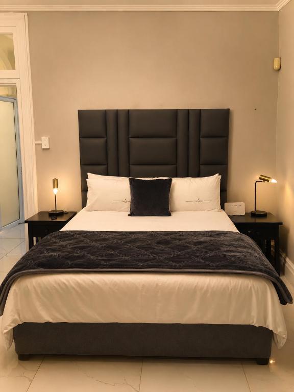 a bedroom with a large bed with a black headboard at Tiah Whyte, Durban in Durban