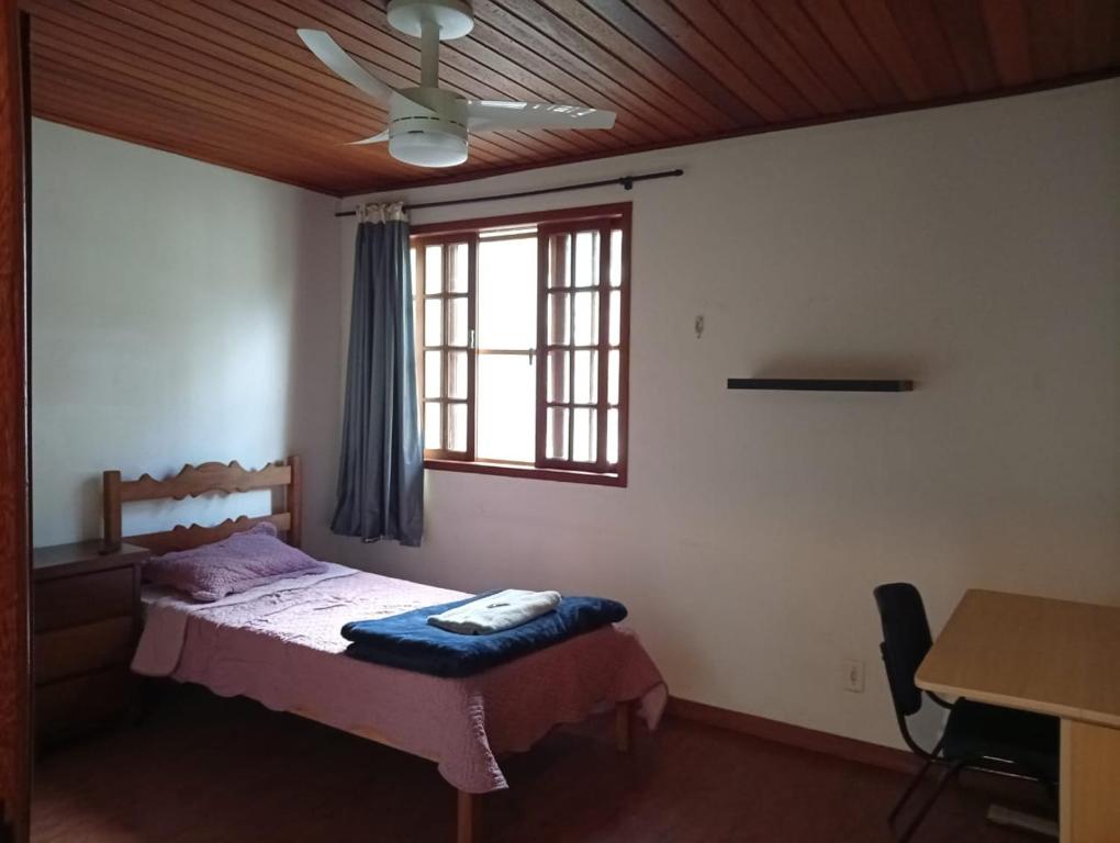 a bedroom with a bed with a ceiling fan and a window at Quarto suite e sala no Centro in Nova Friburgo