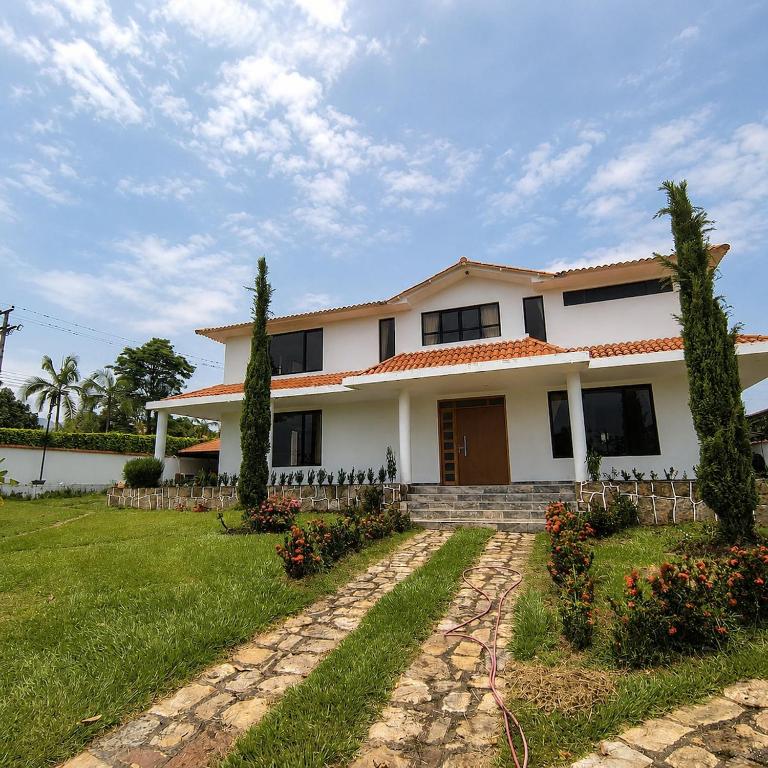 a white house with a yard with a pathway at Villa Conejo Miraflores in Chinauta