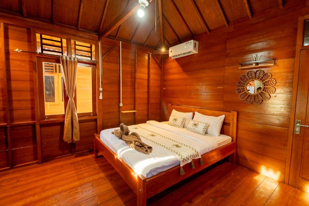 a bedroom with a bed in a wooden room at Westwood Bungalow in Gili Trawangan