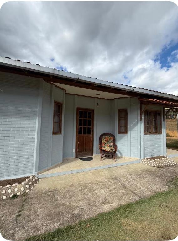 a white house with a chair sitting on a porch at Aconchego Anjo Helena in Domingos Martins